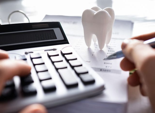 Calculator and dental model on financial documents, illustrating budgeting for dental implants during tax refund season.